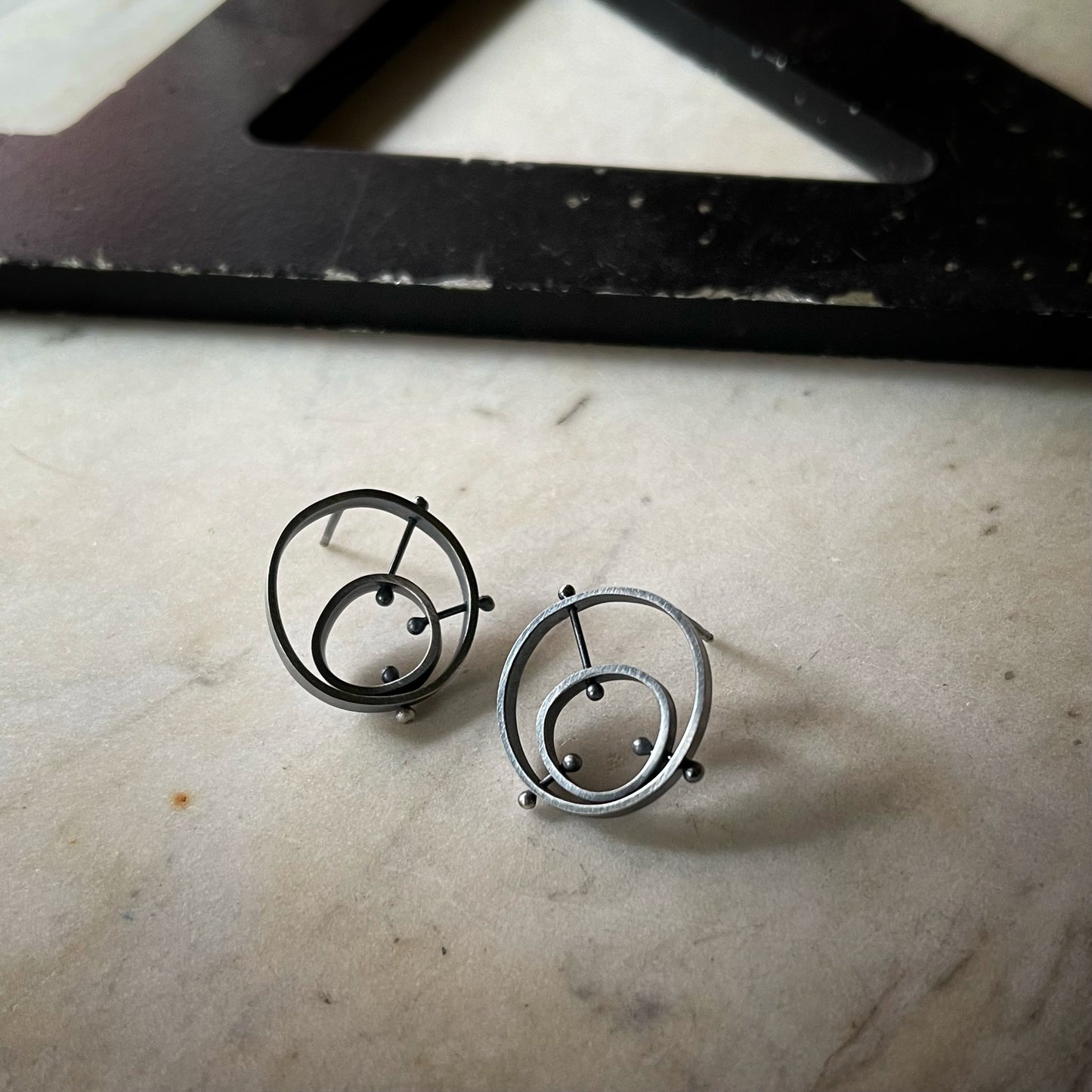 darkened silver earrings with concentric circles held in place by rivets