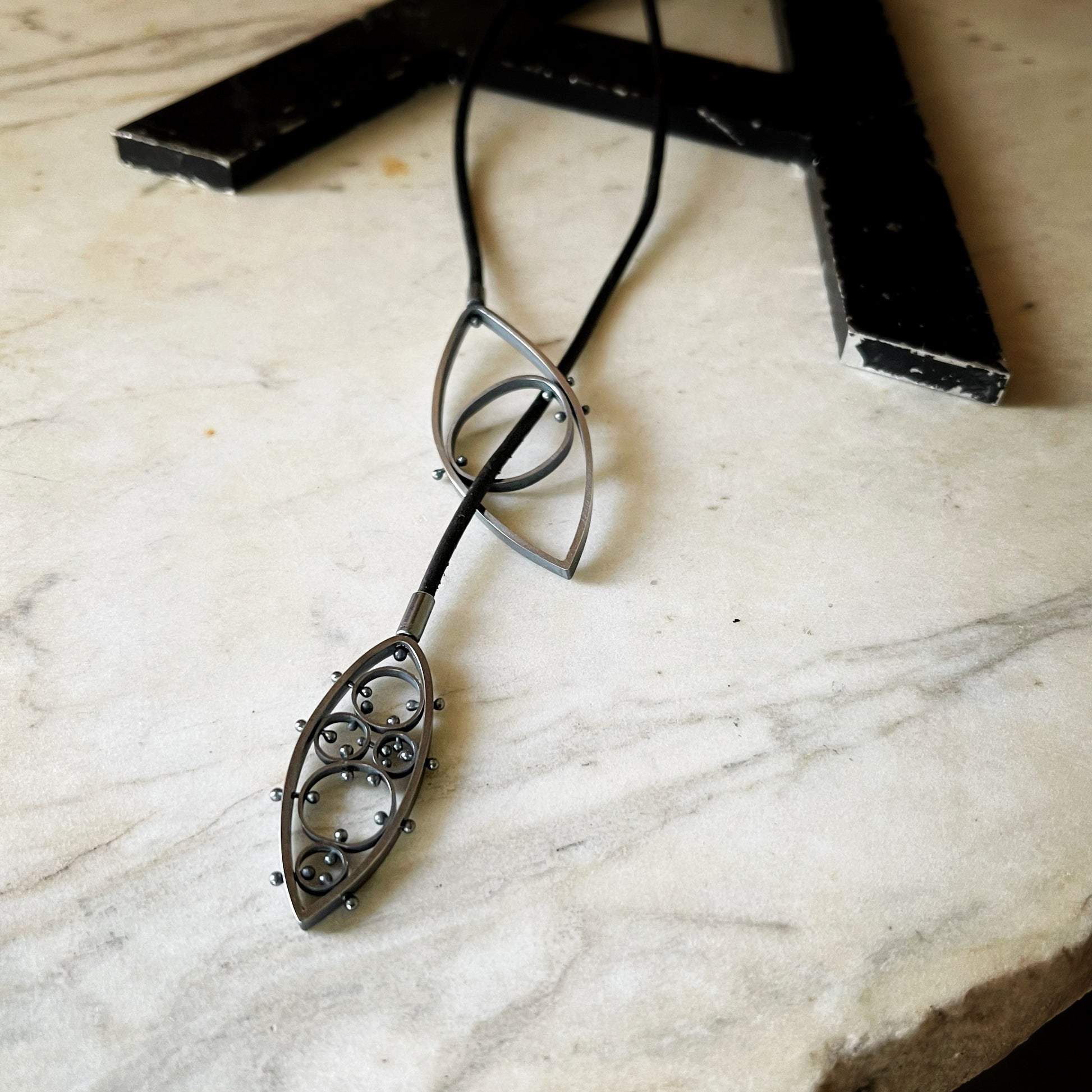 two leaf shaped pendants on a long leather cord.  This shows a third way to wear this necklace