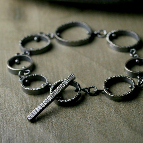 link bracelet made of hammered circle links of different diameters.  oxidized sterling silver.  With toggle