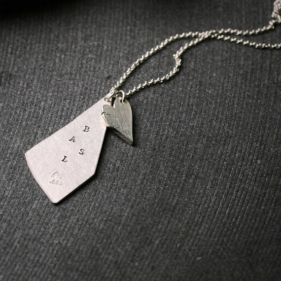 triangular shaped silver pendant with stamped initials and a chunky heart