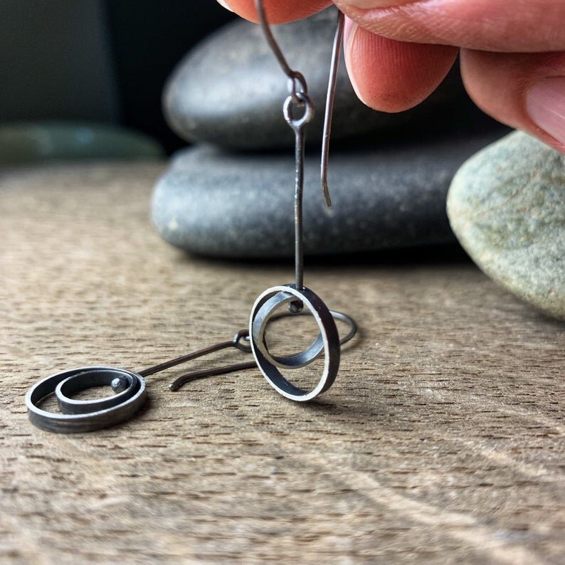 Oxidized sterling silver kinetic earrings shown hanging, demonstrating the moving circles"
