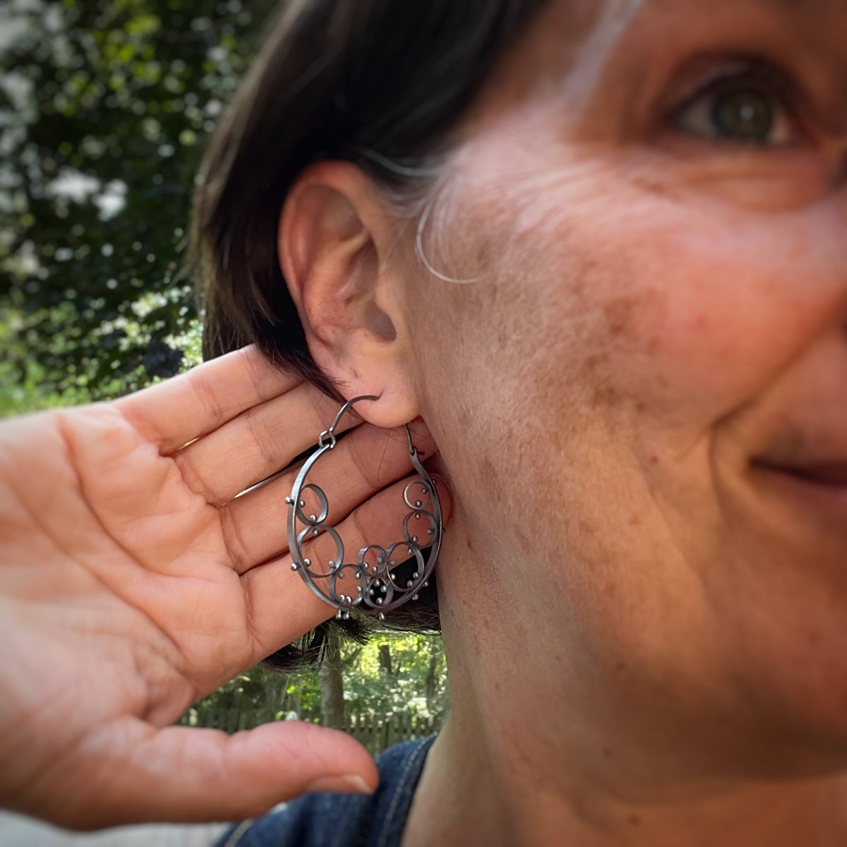 Hoop earrings made of several small riveted cellular circles shown on a model 