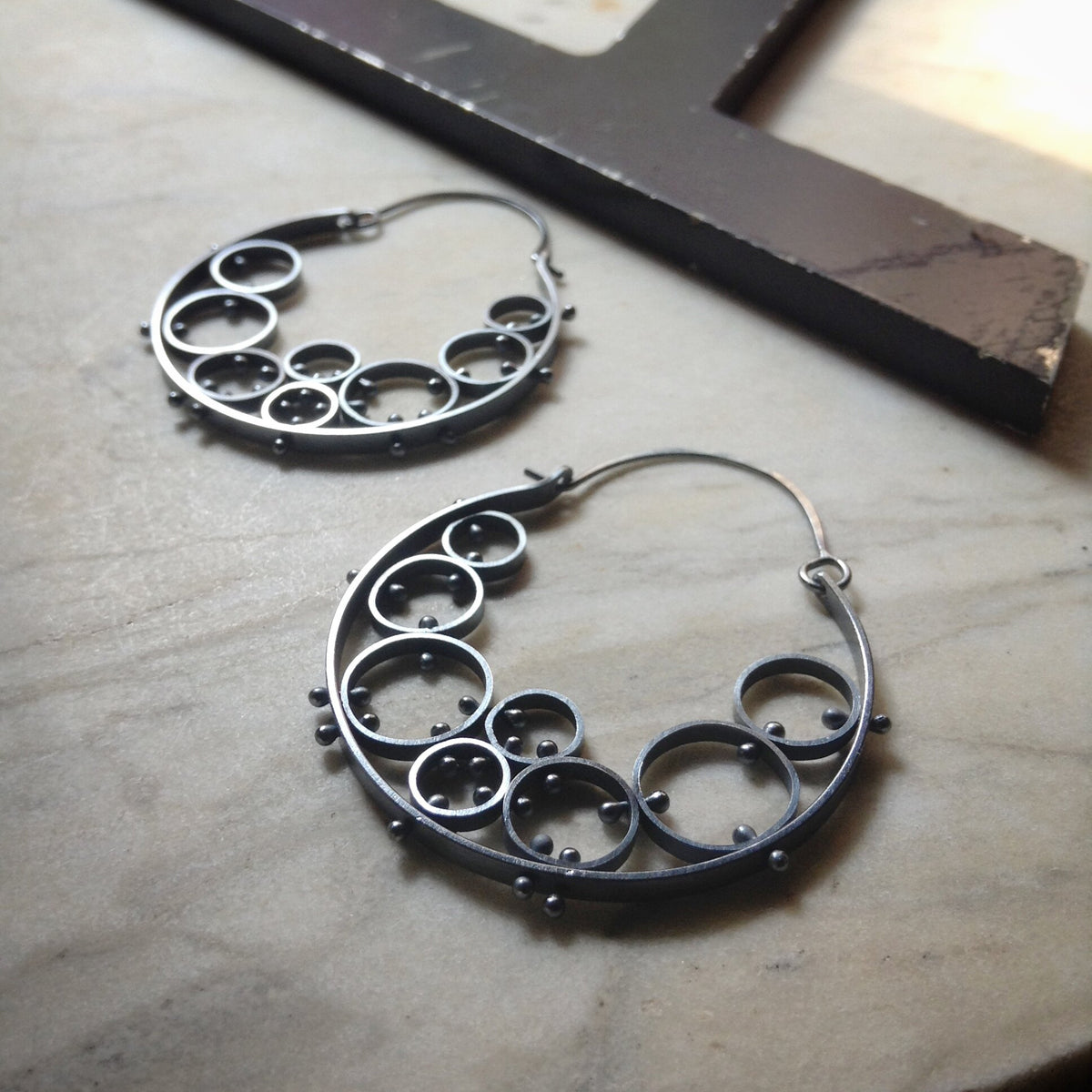 extra large hoop earrings with several riveted circular cells 