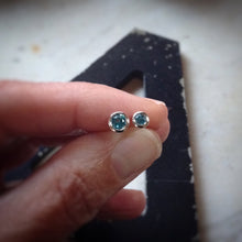 Load image into Gallery viewer, two sizes of bright blue topaz set in sterling silver bezels shown in a hand for scale
