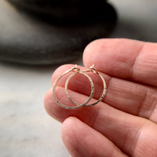 Load image into Gallery viewer, two rose gold hammered hoop earrings shown on a hand for scale
