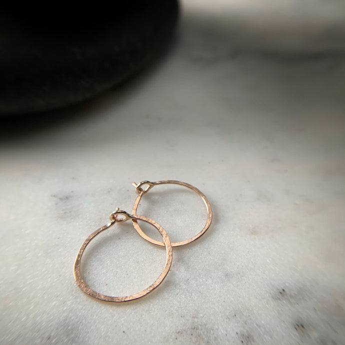 two small hammered rose gold hoops earrings with circular clasps