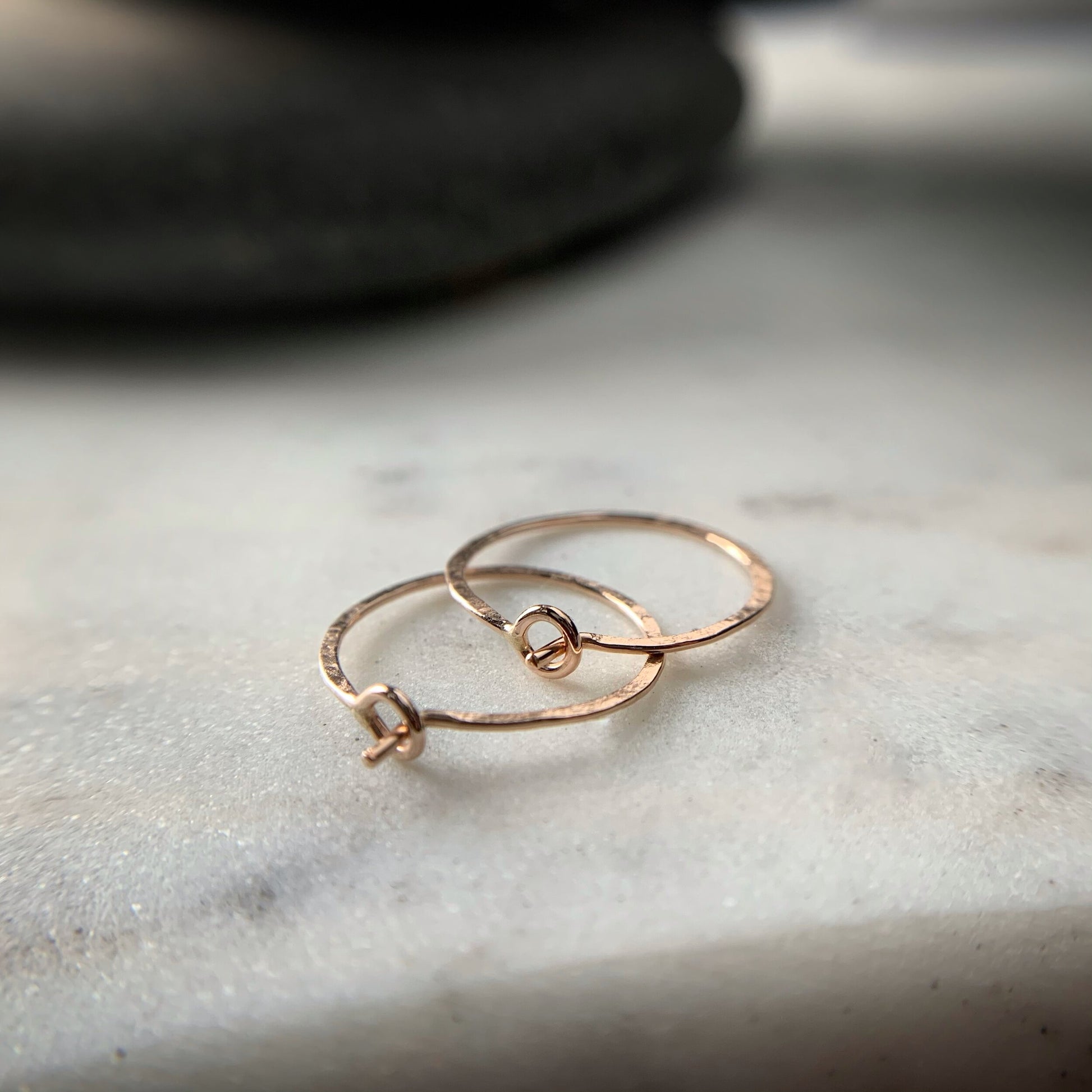 the circular clasps on two rose gold hammered hoop earrings