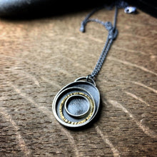 Load image into Gallery viewer, oxidized sterling silver pendant with concentric circles, one in 18k yellow gold with a hammered texture 
