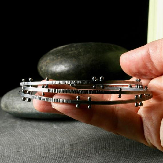 a stack of bangle bracelets with rivets and texture