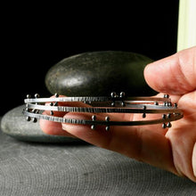 Load image into Gallery viewer, a stack of bangle bracelets with rivets and texture
