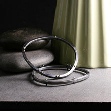 Load image into Gallery viewer, two bracelets shown from above to show the asymmetrical shape and the rivets

