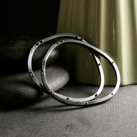 two heavyweight asymmetrical bangle bracelets with both silver and gold rivets