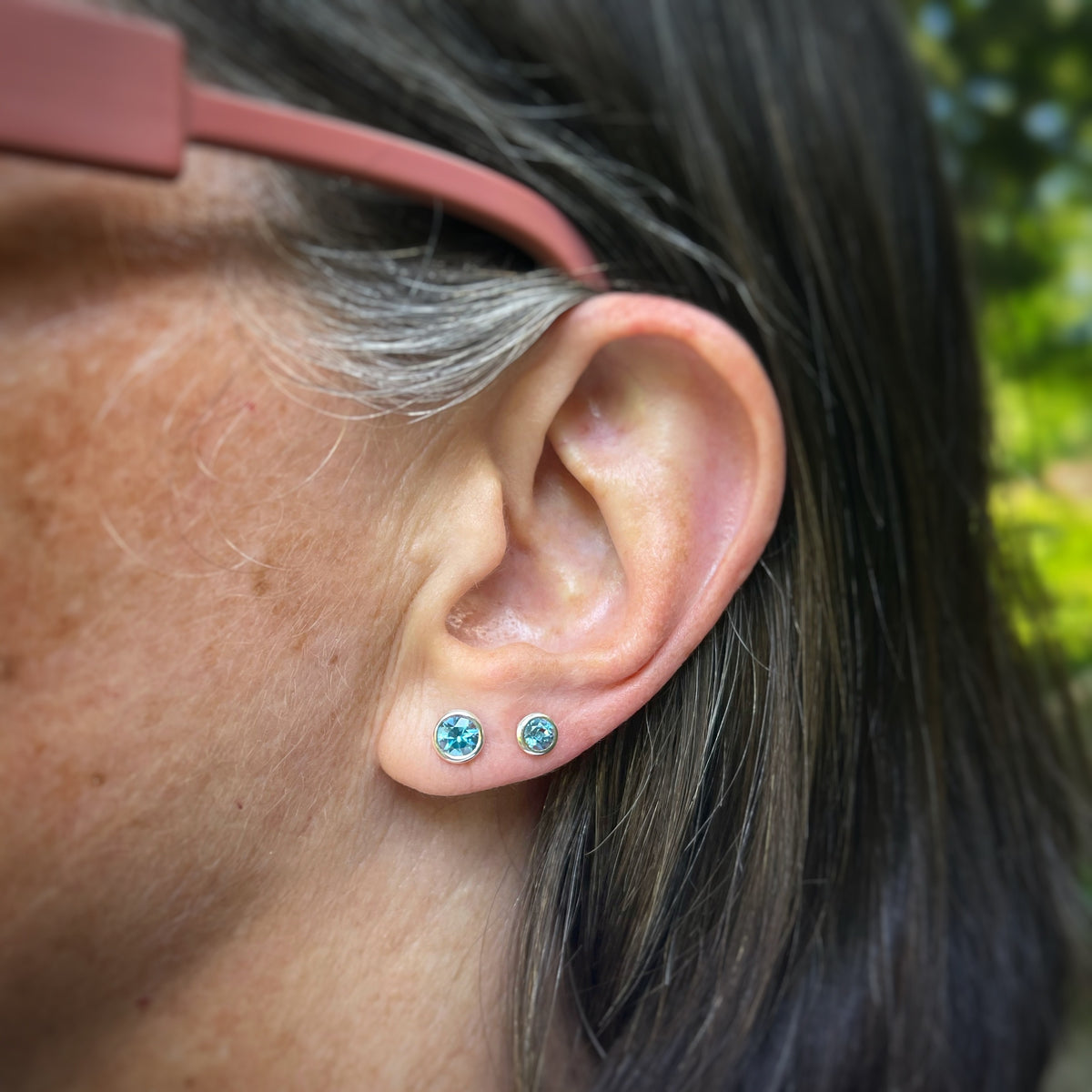 4mm and 5mm Swiss blue topaz earrings shown on an ear for scale 