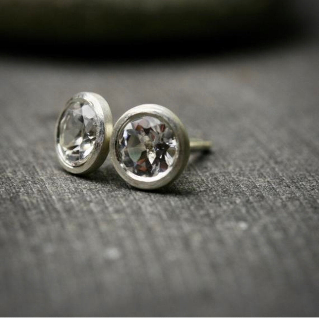 bezel set white topaz stud earrings in sterling silver shown from the side to show earring posts