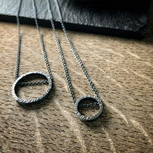 Load image into Gallery viewer, two pendants, one large and one small, in sterling silver.  They are circles with a hammered texture and the chain runs through the circle.  Both are oxidized silver.
