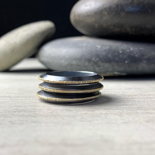 a stack of three rings with a triangular profile, edged with hammered 18k yellow gold