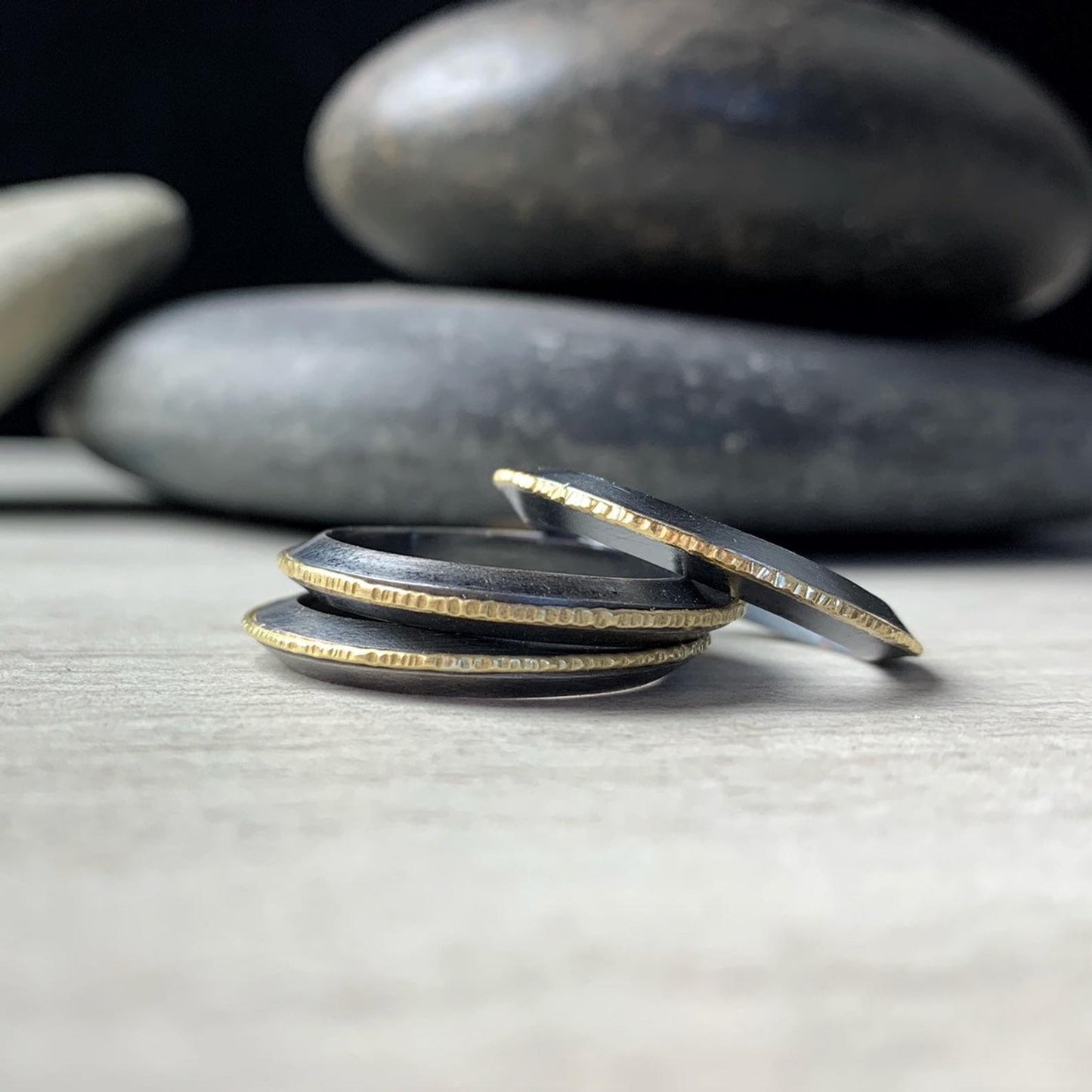 stack of three modern rings in 18k yellow gold and darkened silver