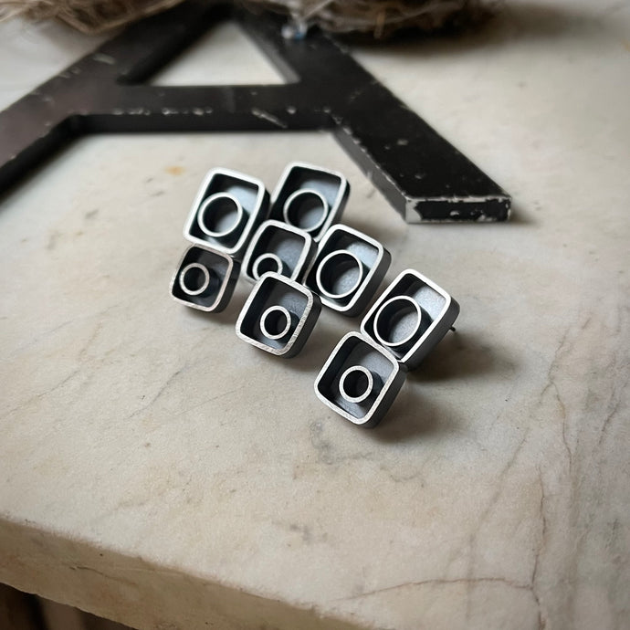 a group of all 4 pairs of asymmetrical earrings.  They have a square shape with a circle off center.
