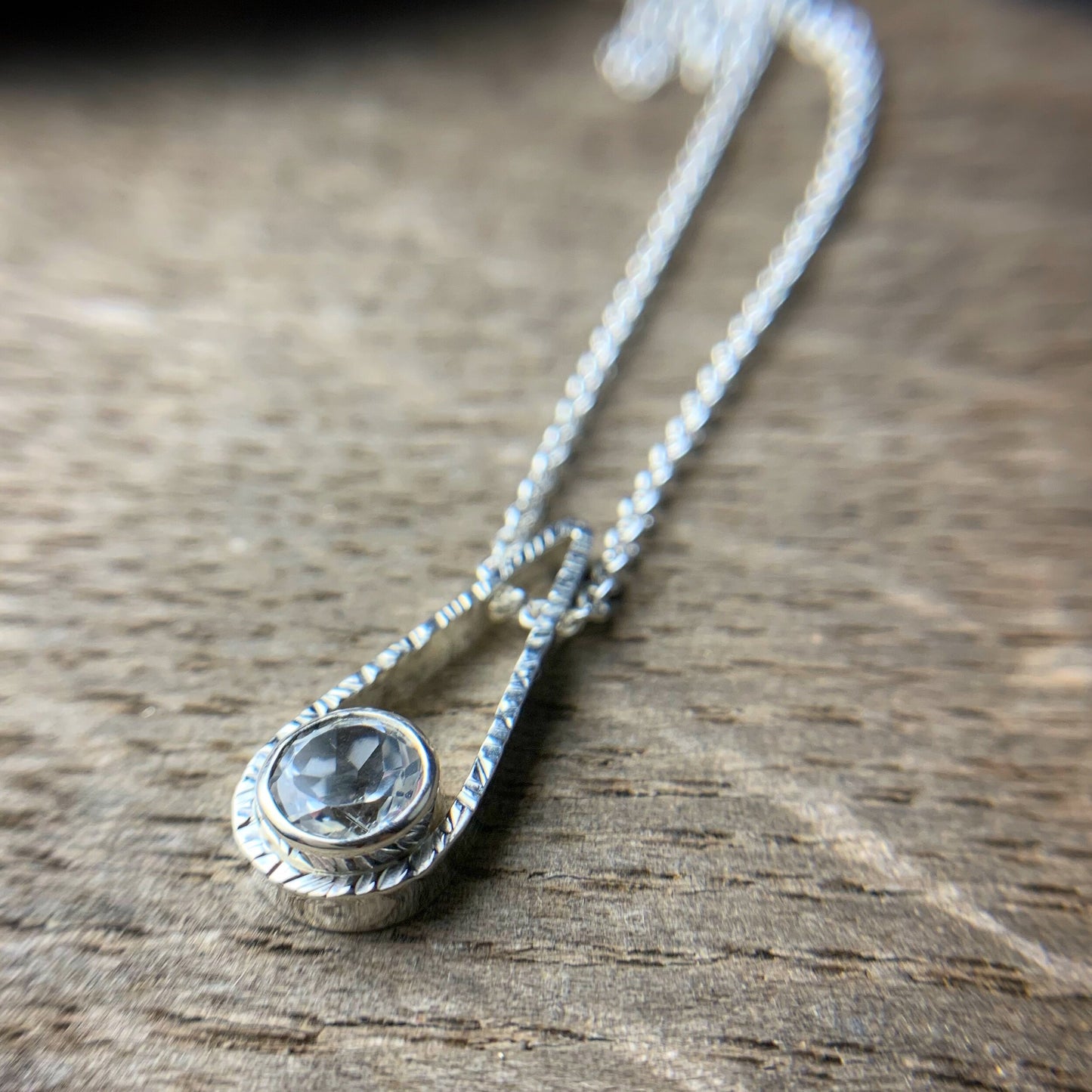 6mm bezel set white topaz in a textured teardrop pendant